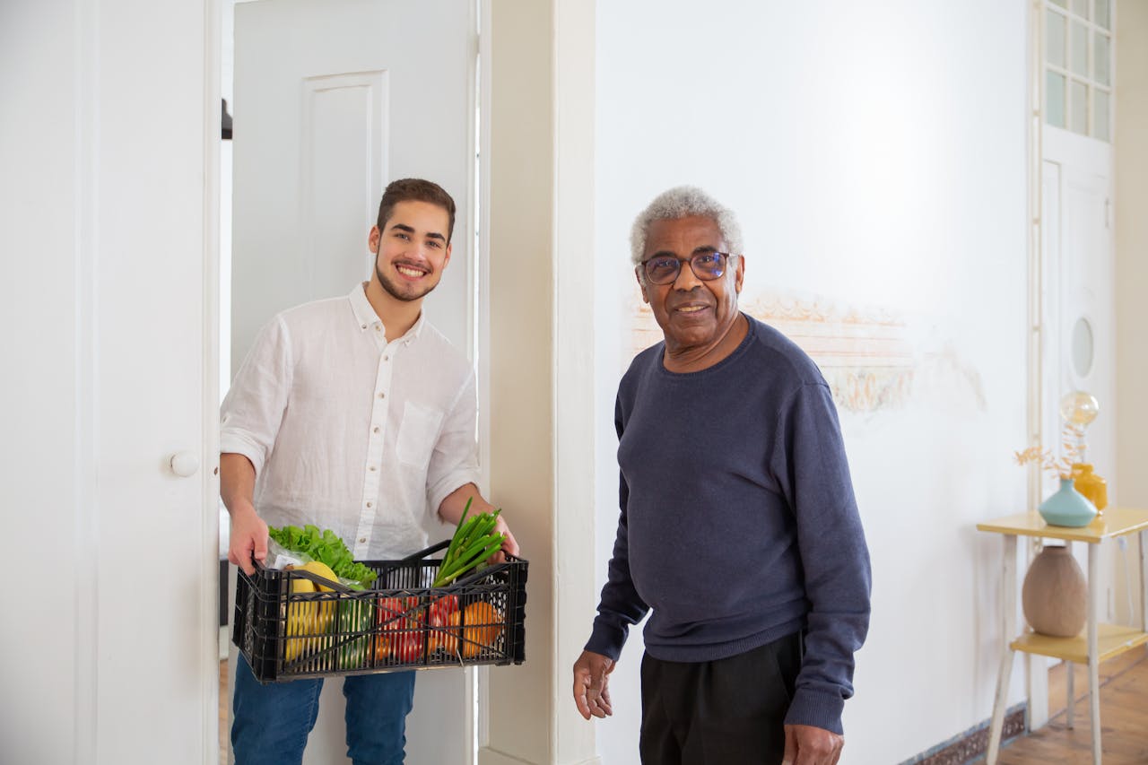 About Senior man receiving fresh produce from a young volunteer indoors, promoting community support.